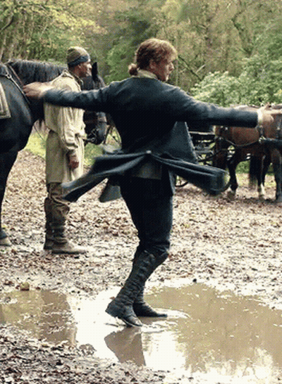 Man In Black Coat Standing In Muddy Puddle GIF
