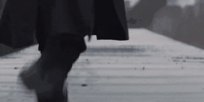 Man In Black Coat Walking Down Sidewalk Black And White Photo GIF