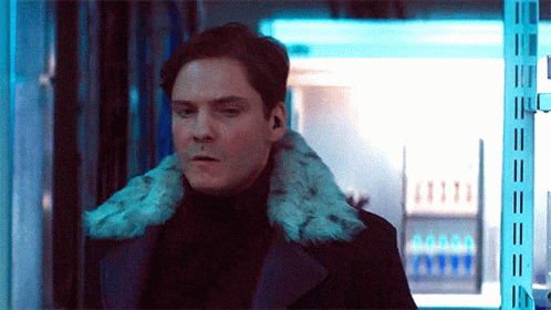 Man In Black Coat With Fur Collar Standing In Room GIF