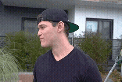 Man In Black Hat And Black Shirt Before House GIF