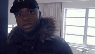 Man In Black Hat And Fur Hood Jacket By Window GIF