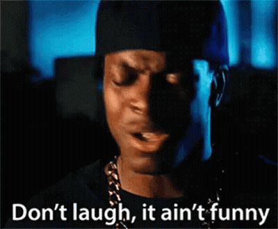 Man In Black Hat And Gold Chain Says Don't Laugh It Ain't Funny GIF