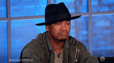 Man In Black Hat And Green Jacket Sitting At Window Saying World Of Dance GIF