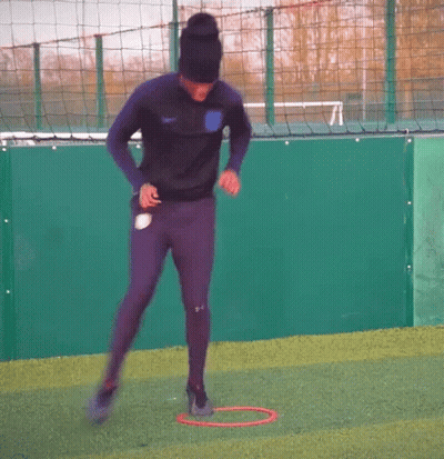 Man In Black Hat Jumping Through Red Hoop On Soccer Field GIF
