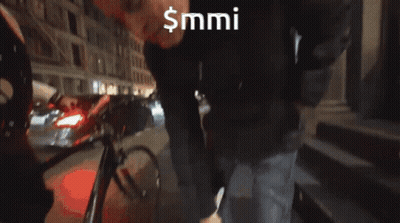 Man In Black Hat Standing In Front Of $MMI Sign GIF