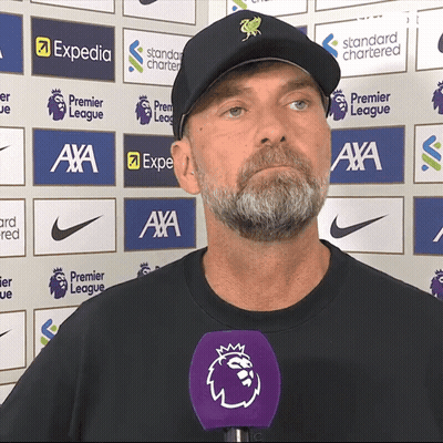 Man In Black Hat With Purple Mic In Front Of Expedia And Standard Chartered Logos GIF