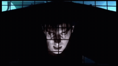 Man In Black Hood Standing In Front Of Window GIF