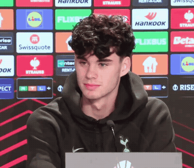Man In Black Hoodie In Front Of Logo Wall GIF