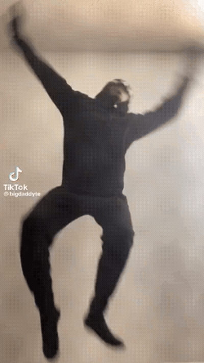 Man In Black Hoodie Jumping With Arms Outstretched GIF