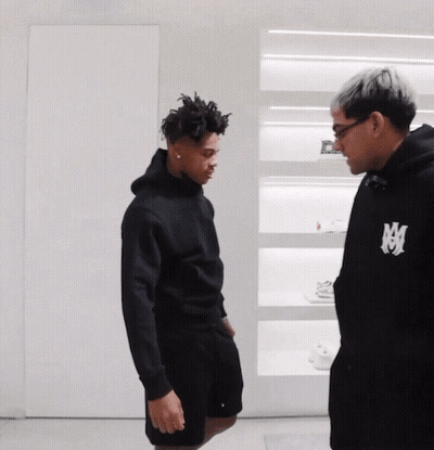Man In Black Hoodie With Letter M Talks To Another Man GIF