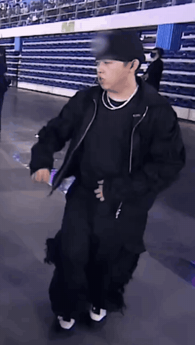 Man In Black Jacket And Hat Holding Water Bottle In Stadium GIF