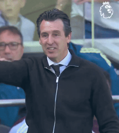 Man In Black Jacket And Tie Arm Outstretched In Stadium GIF