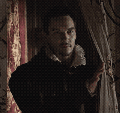 Man In Black Jacket And White Collar Standing By Window GIF