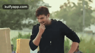 Man In Black Jacket Eating In Front Of Box GIF