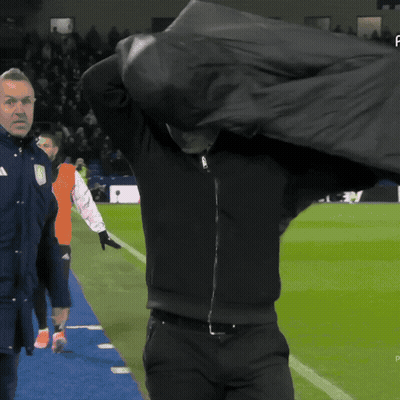 Man In Black Jacket Holding Bag Over Head On Soccer Field GIF
