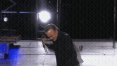 Man In Black Jacket Holding Microphone On Stage GIF