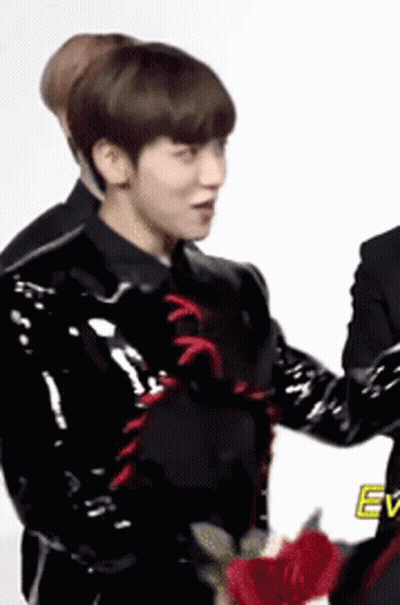 Man In Black Jacket Holding Red Flower Next To Another Man GIF