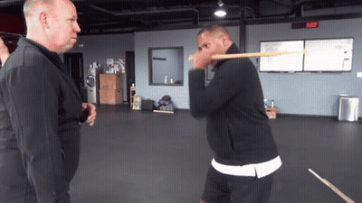 Man In Black Jacket Holding Stick To Face GIF