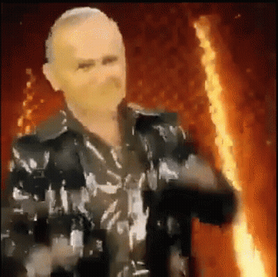 Man In Black Jacket Holding Torch In Front Of Fire GIF
