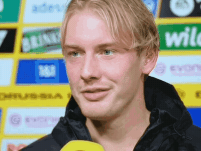 Man In Black Jacket In Front Of Yellow Wild Sign GIF