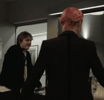 Man In Black Jacket Next To Woman With Pink Hair GIF
