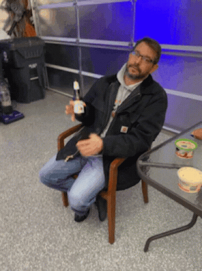Man In Black Jacket Sitting Holding Bottle GIF