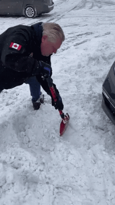 Man In Black Jacket With Canadian Flag Shoveling Snow GIF
