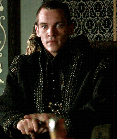 Man In Black Jacket With Gold Beads Sitting In Chair GIF