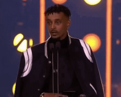 Man In Black Jacket With Two Microphones GIF