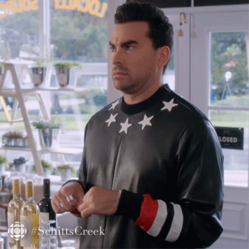 Man In Black Jacket With White Stars Standing In Front Of Closed Sign GIF