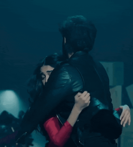 Man In Black Leather Jacket Hugging Woman In Red Dress GIF