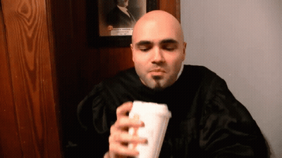 Man In Black Robe Holding Cup In Front Of Portrait GIF