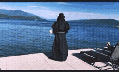 Man In Black Robe On Dock Overlooking Lake GIF