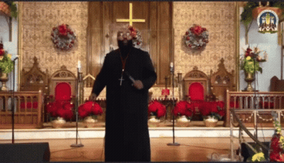 Man In Black Robe Standing In Front Of Church With Cross GIF
