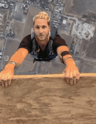 Man In Black Shirt And Blue Backpack Hanging Off Wall GIF