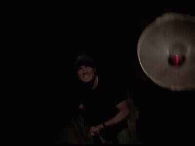 Man In Black Shirt And Blue Hat With Red Light Behind GIF