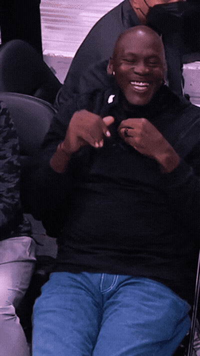 Man In Black Shirt And Blue Jeans Smiling In Chair GIF