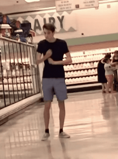 Man In Black Shirt And Blue Shorts At Dairy Sign GIF