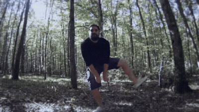 Man In Black Shirt And Blue Shorts Standing In Forest GIF