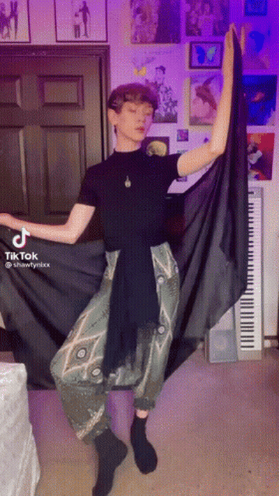 Man In Black Shirt And Green Pants Standing At Piano GIF