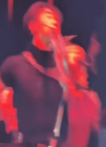 Man In Black Shirt And Pants Cross-Legged On Stage GIF