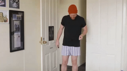 Man In Black Shirt And Striped Shorts In Hallway GIF