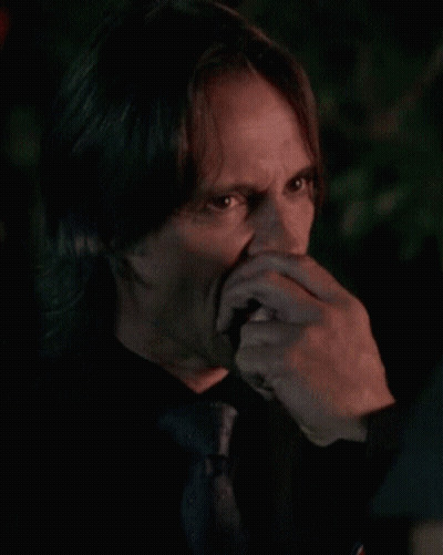 Man In Black Shirt And Tie Biting Food GIF