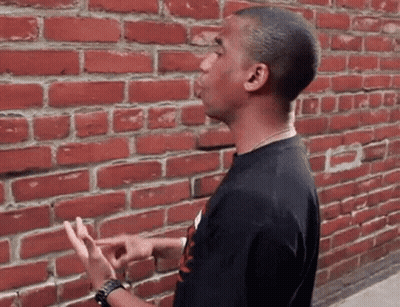 Man In Black Shirt By Brick Wall GIF