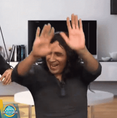 Man In Black Shirt Dancing In Front Of Venga La Alegria Sign GIF
