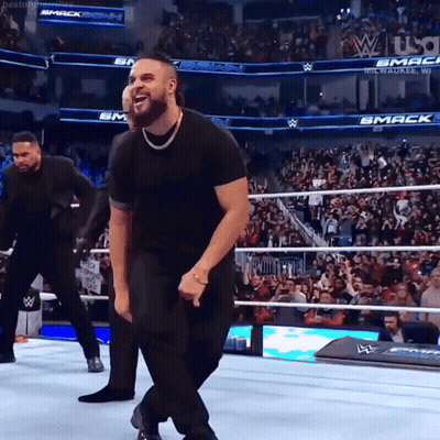 Man In Black Shirt Dancing In Wrestling Ring With Smack Sign GIF