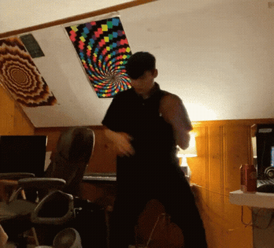 Man In Black Shirt Dancing Under Colorful Swirl Ceiling GIF