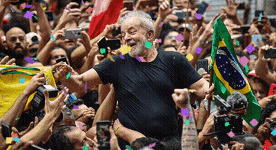 Man In Black Shirt Holding Brazilian Flag In Front Of Crowd GIF