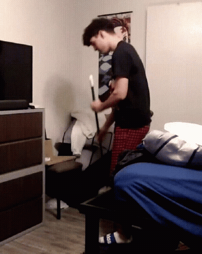 Man In Black Shirt Holding Cane In Bedroom GIF