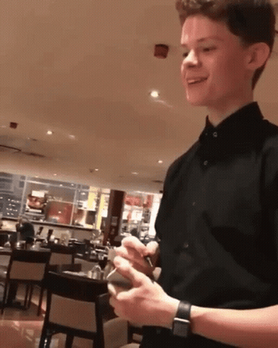 Man In Black Shirt Holding Cell Phone In Restaurant GIF